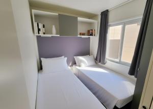 zwei Betten in einem kleinen Zimmer mit Fenster in der Unterkunft Bungalow e Mobilhome - Camper Park 2 in Rimini