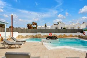 a swimming pool with two lounge chairs next to a building at Apartamentos LIVVO Mar Azul - Adults Only in Corralejo