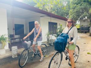 duas mulheres a andar de bicicleta em frente a uma casa em The Lavish Polonnaruwa em Polonnaruwa