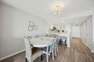 a dining room and kitchen with a white table and chairs at Beach Cottage Look Condo, Ocean View from Spacious Balcony in Fernandina Beach