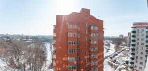 Un edificio alto de ladrillo rojo con nieve en el suelo. en Luxury 1-bd Apartment Novomestenska Street, en Sumy
