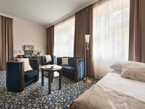 Una habitación de hotel con una cama, un sofá y sillas. en Hotel Esprit, en Praga
