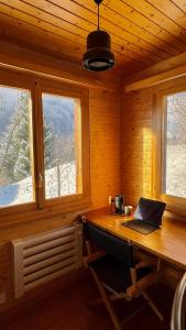 Una computadora portátil sobre un escritorio de madera en una habitación con ventanas. en Chalet Montis, en Bellwald