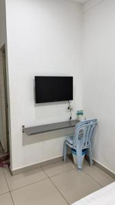 una tv su una parete con una sedia blu e una tv di Syt Hotel a Banting