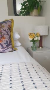 ein weißes Bett mit einem Kissen und einer Blumenvase in der Unterkunft The Meads in Ilfracombe