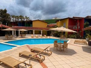 a swimming pool with chairs and tables and umbrellas at Girassol Praia Hotel in Porto Seguro