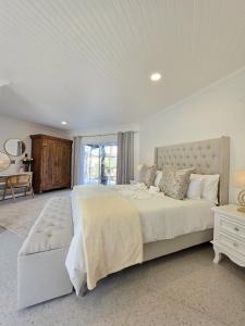 White Cottage Boutique Guesthouse في سواكوبموند: غرفة نوم بيضاء كبيرة مع سرير كبير ومكتب