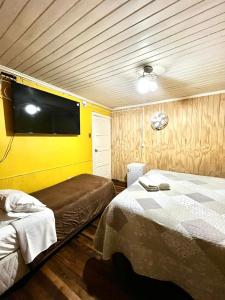 a bedroom with two beds and a flat screen tv at Hostal Las Heras in Temuco +41 photos