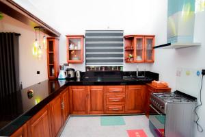 eine Küche mit Holzschränken und schwarzen Arbeitsplatten in der Unterkunft Iman House in Nikawatawana