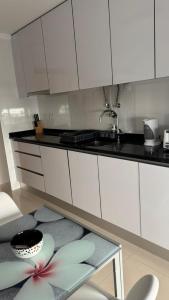 une cuisine avec des armoires blanches et une table en verre dans l'établissement Laguna mar beach house, à Monte Gordo