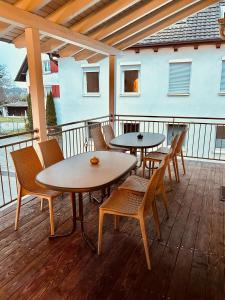 two tables and chairs on a deck with a building at Pension Mimosa in Rust