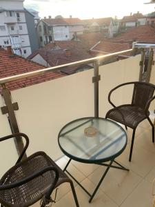 ein Glastisch und zwei Stühle auf einem Balkon in der Unterkunft City Comfort Apartment in Vranje