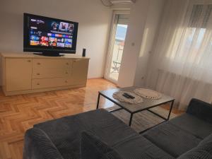 ein Wohnzimmer mit einem Sofa und einem TV auf einer Kommode in der Unterkunft City Comfort Apartment in Vranje