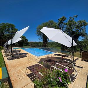 two white umbrellas and chairs next to a pool at Tupa Lodge Selva y Rio in Puerto Iguazú +50 photos