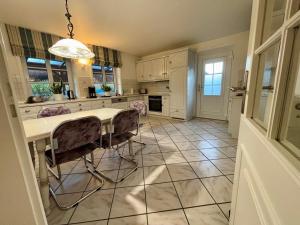 a kitchen with a table and chairs on a tiled floor at 108 qm EG-Fewo mit Garten - Grill - Westterrassen in Oevenum