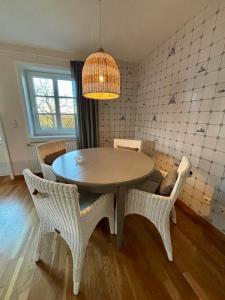 a dining room table with wicker chairs and a light fixture at 108 qm EG-Fewo mit Garten - Grill - Westterrassen in Oevenum +6 photos