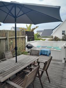 a wooden picnic table with an umbrella on a deck at Sunbird 2 in Cape St Francis