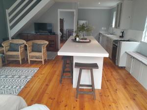 a kitchen with a white counter and chairs in a room at Sunbird 2 in Cape St Francis