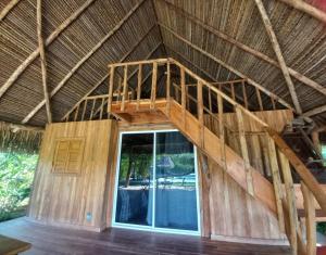 a room in a straw roofed house with a staircase at Finca Zayan in El Copé