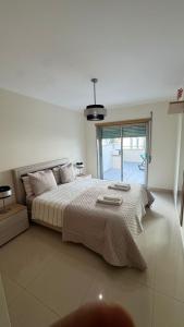 une chambre avec un grand lit et une grande fenêtre dans l'établissement Laguna mar beach house, à Monte Gordo