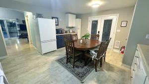 Waterfront 2-BR Cottage Retreat in Manitoulin Island في Kagawong: مطبخ مع طاولة خشبية وثلاجة بيضاء