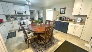 Waterfront 2-BR Cottage Retreat in Manitoulin Island في Kagawong: مطبخ مع طاولة خشبية ومطبخ مع دواليب بيضاء