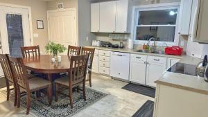 Waterfront 2-BR Cottage Retreat in Manitoulin Island في Kagawong: مطبخ مع طاولة وكراسي ومطبخ مع دواليب بيضاء +18 صورة