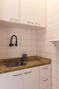 a kitchen counter with a sink and white cabinets at 4 minutos da Praia de Copacabana - NSC803 in Rio de Janeiro +12 photos