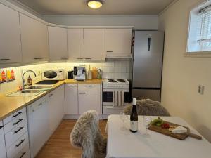 a kitchen with white cabinets and a table with a bottle of wine at Cozy Central Apartment - Free Parking & Wifi in Vossevangen