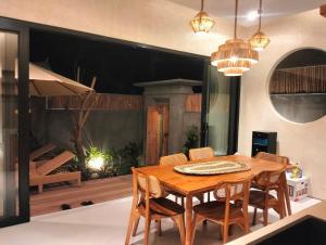 a dining room with a wooden table and chairs at Villa Puri Mesari Amed in Amed