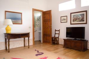 ein Wohnzimmer mit einem TV, einem Tisch und einem Schreibtisch in der Unterkunft Casale Cipresso in Migliarino