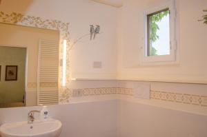 ein weißes Badezimmer mit Waschbecken und Fenster in der Unterkunft Casale Cipresso in Migliarino + 37 Fotos