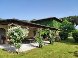 ein Haus mit einem Tisch und Blumen im Hof in der Unterkunft Casale Cipresso in Migliarino