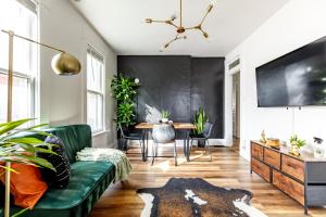 a living room with a green couch and a table at Jungle House Columbus Sleep 16 Downtown Ohio Free Parking - Near Convention Center & Nationwide Arena - 4BR Luxury Home - Pet Friendly - Over 5,800 Five Stars in Columbus