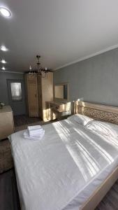 Un dormitorio con una gran cama blanca en una habitación. en Люкс 2х комнатная квартира, en Taraz