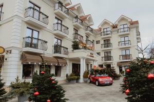 莱斯诺夫瑞萨酒店的一辆红色汽车停在一栋摆放着圣诞树的建筑物前。