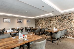 un restaurante con mesas y sillas de madera y una pared de piedra. en Seacote Hotel, en St Bees 28 fotos más