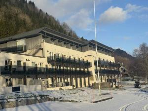 a large building in front of a mountain at Resort by the Lake - Pool & Sauna in Vossevangen
