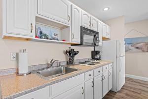 a kitchen with white cabinets and a sink and a refrigerator at Torch Lake Vista A-Ga-Ming Golf Retreat 741 in Creswell