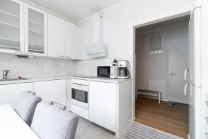 a white kitchen with white cabinets and a microwave at City Pearl in Jyväskylä