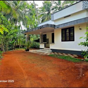 a house with a red dirt road in front of it at Thiruthi Homestay in Vallikunnu