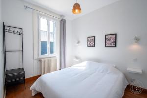 ein weißes Schlafzimmer mit einem Bett und einem Fenster in der Unterkunft Maison Le Damier - Proche Center Parcs et Lamotte Beuvron - 3 chambres in La Ferté-Saint-Aubin