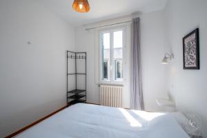 ein weißes Schlafzimmer mit einem Bett und einem Fenster in der Unterkunft Maison Le Damier - Proche Center Parcs et Lamotte Beuvron - 3 chambres in La Ferté-Saint-Aubin