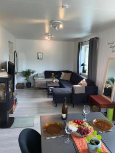 ein Wohnzimmer mit einem Sofa und einem Tisch mit Weingläsern in der Unterkunft Stylish central penthouse - River views in Vossevangen