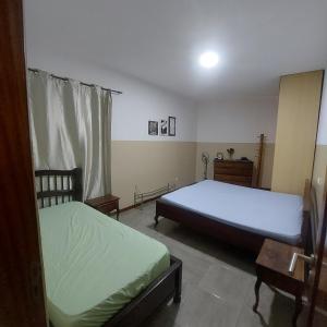 a bedroom with two beds and a table and a mirror at Oia Mindelo Chambre d'hotes in Mindelo