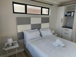 a bedroom with a large white bed with two towels on it at Cosmic View Lodge in East London