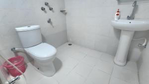 a white bathroom with a toilet and a sink at Hotel Lynn Valley in Bogra