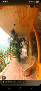 a balcony with a chair on a wooden deck at The Cedar Nook Tree House in Jibhi