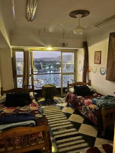 a room with two beds and a large window at Aisha guesthouse in Aswan +14 photos