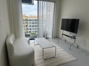 un soggiorno con sedia bianca e TV di Căn nhà nhỏ a Long Bình